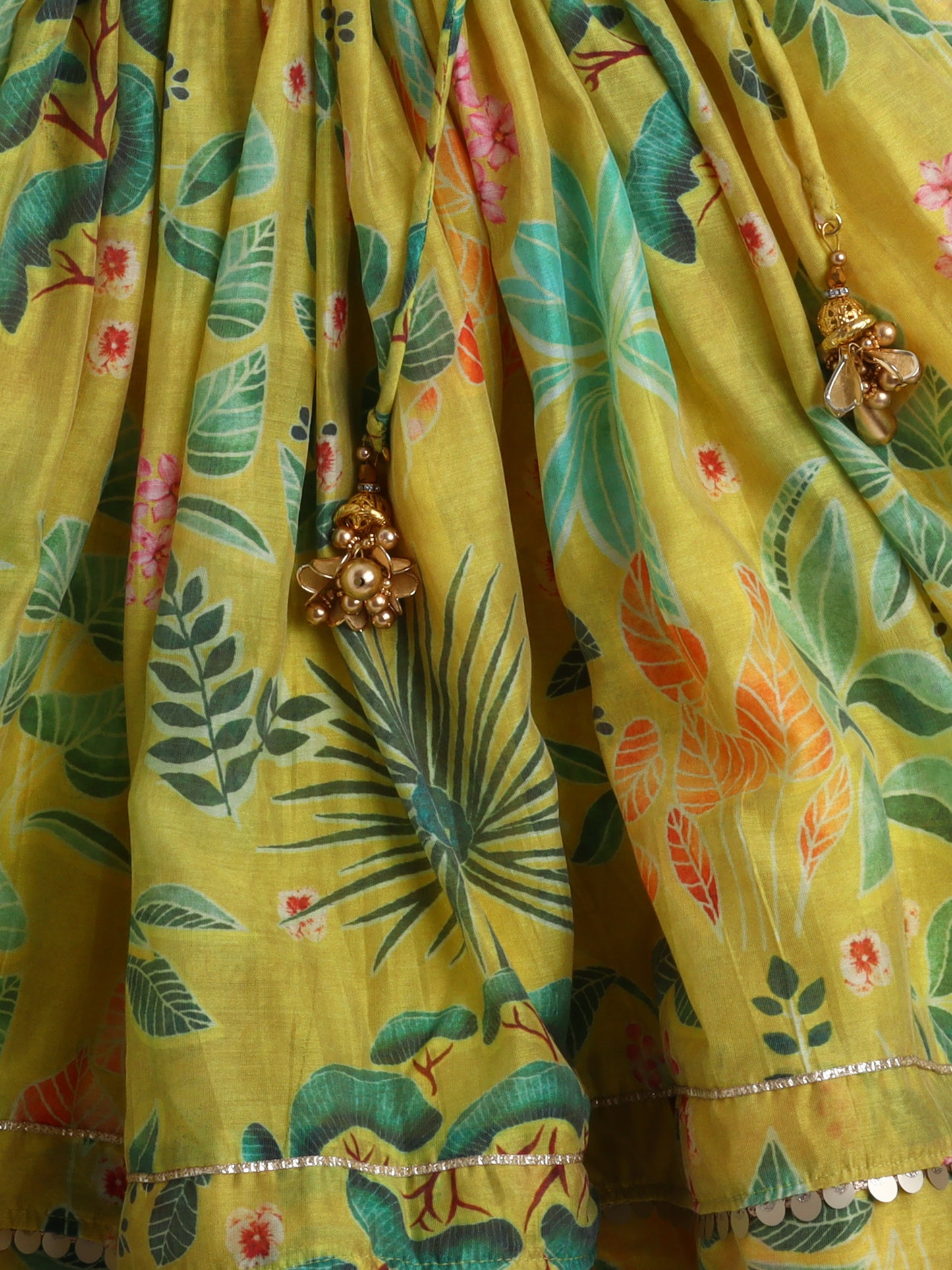 Yellow fabric with floral and leaf patterns and gold jewelry.
