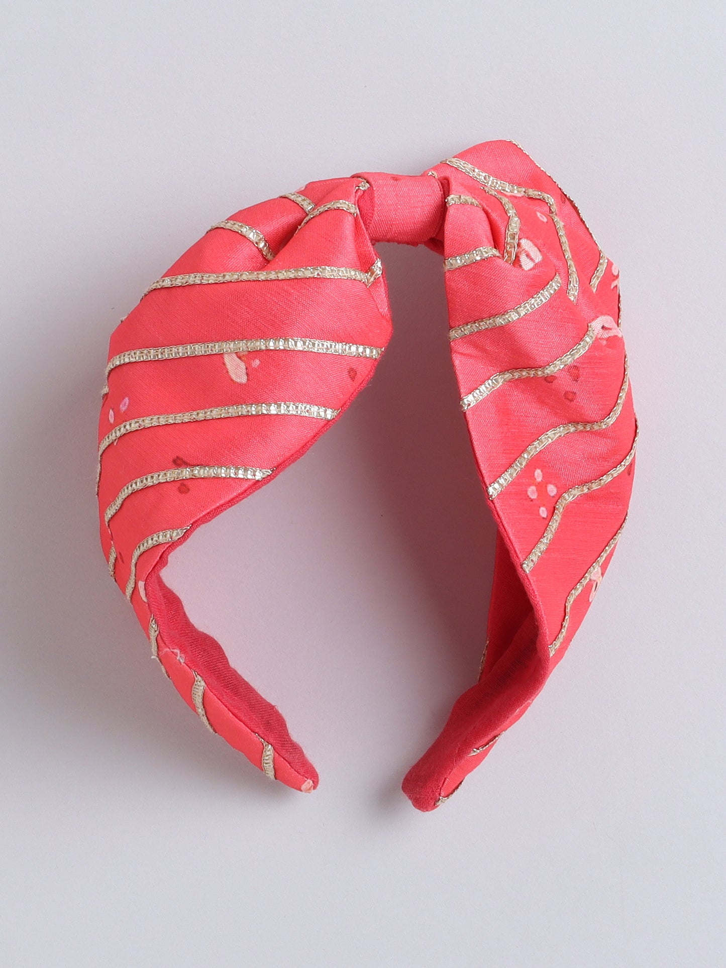 Pink headband with gold stripes on a light gray background