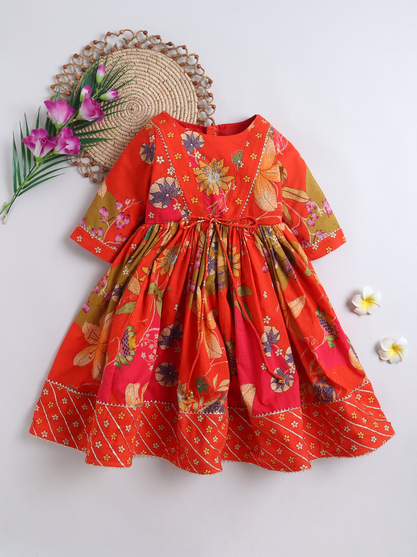 Red floral dress on a white background with decorative elements.