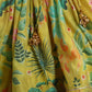 Yellow fabric with floral and leaf patterns and gold jewelry.