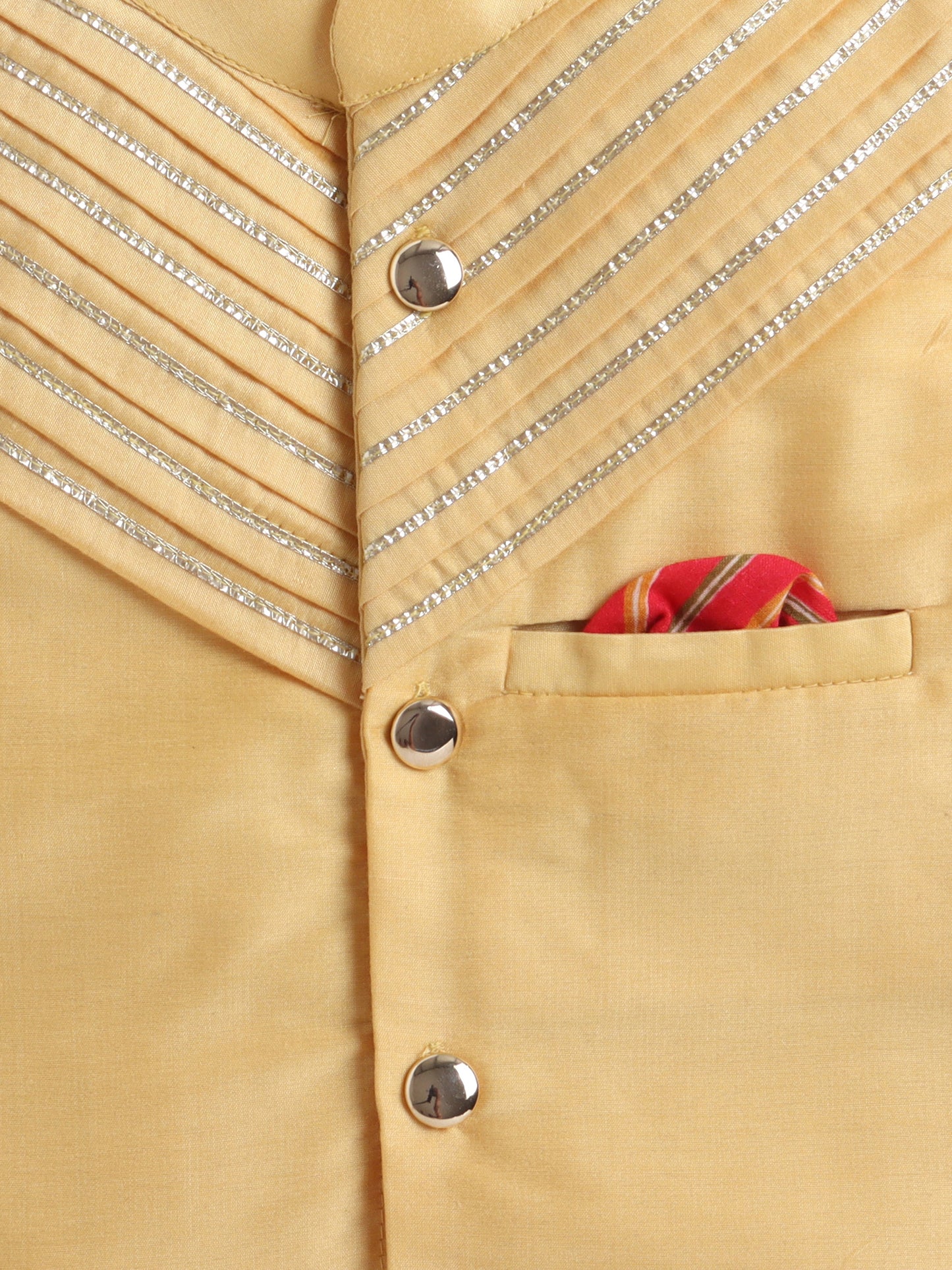 Close-up of a beige jacket with decorative buttons and a pocket featuring a red and gold handkerchief.