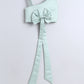 Mint green one-shoulder top with a large bow on a light gray background