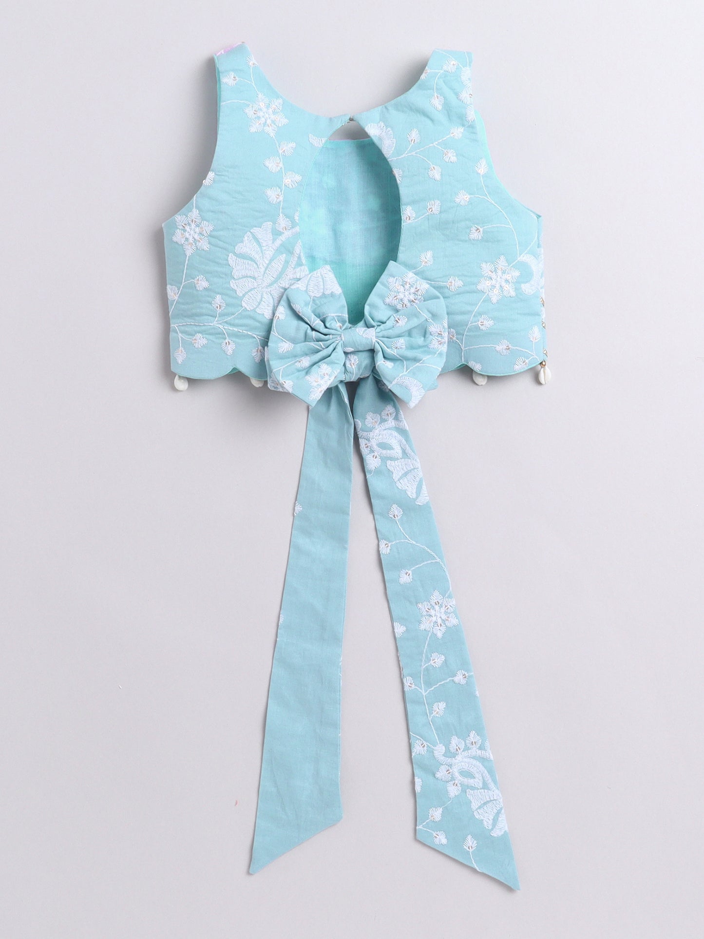 Light blue floral top with a large bow on a light gray background