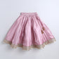 Pink skirt with gold lace trim on a white background
