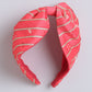Pink headband with gold stripes on a light gray background