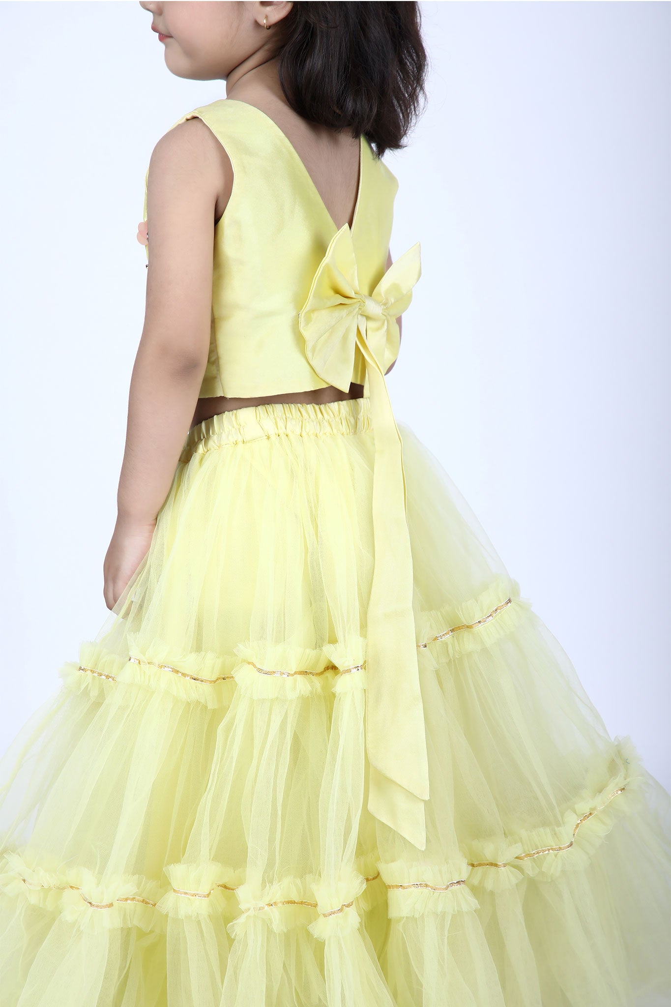 Side view highlighting yellow lehenga’s blouse with a bow. elastic waist with ornate ruffle's.