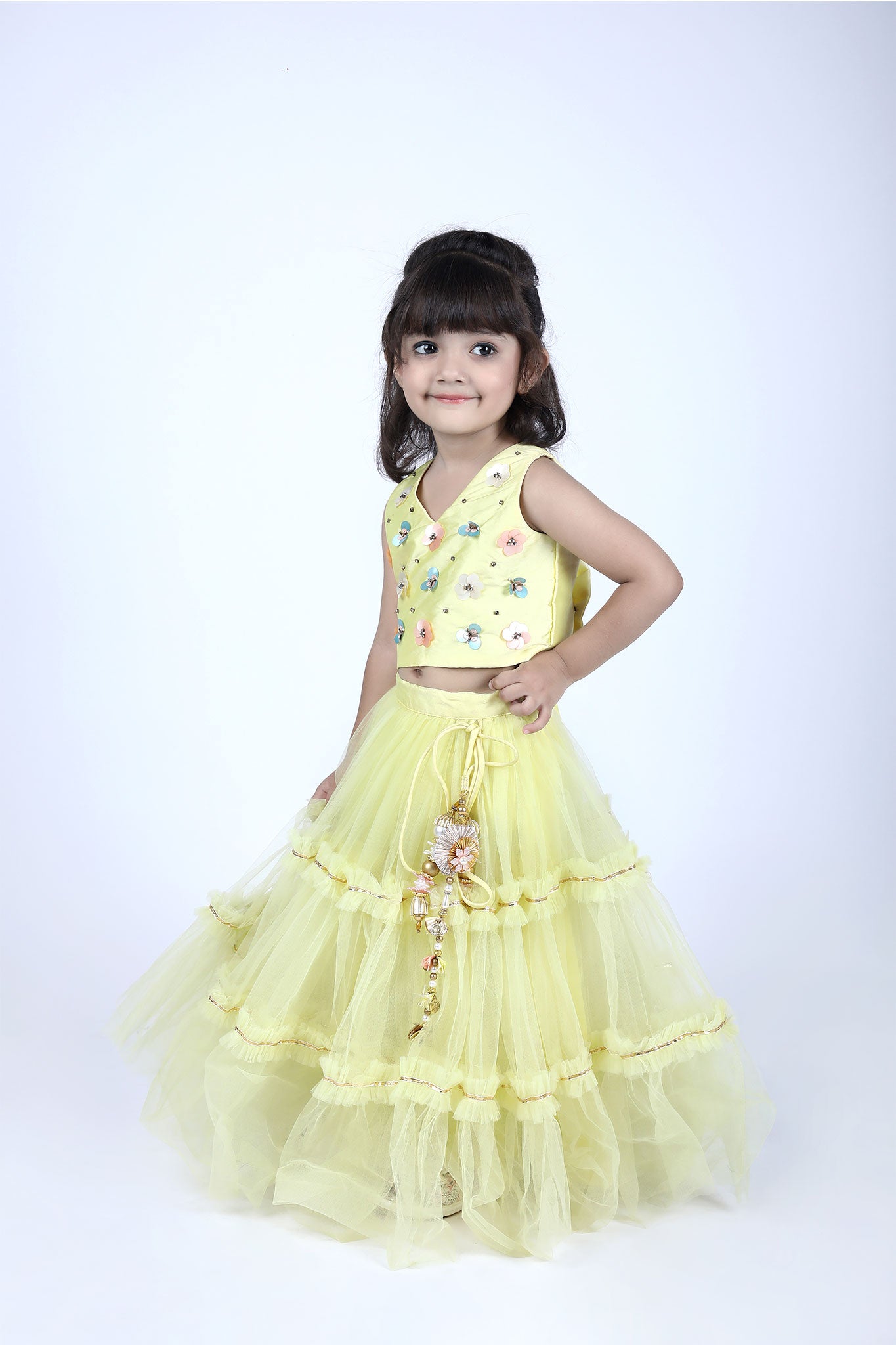 Side view highlighting yellow lehenga’s drawstring waist with ornate tassels, paired with floral embroidered blouse